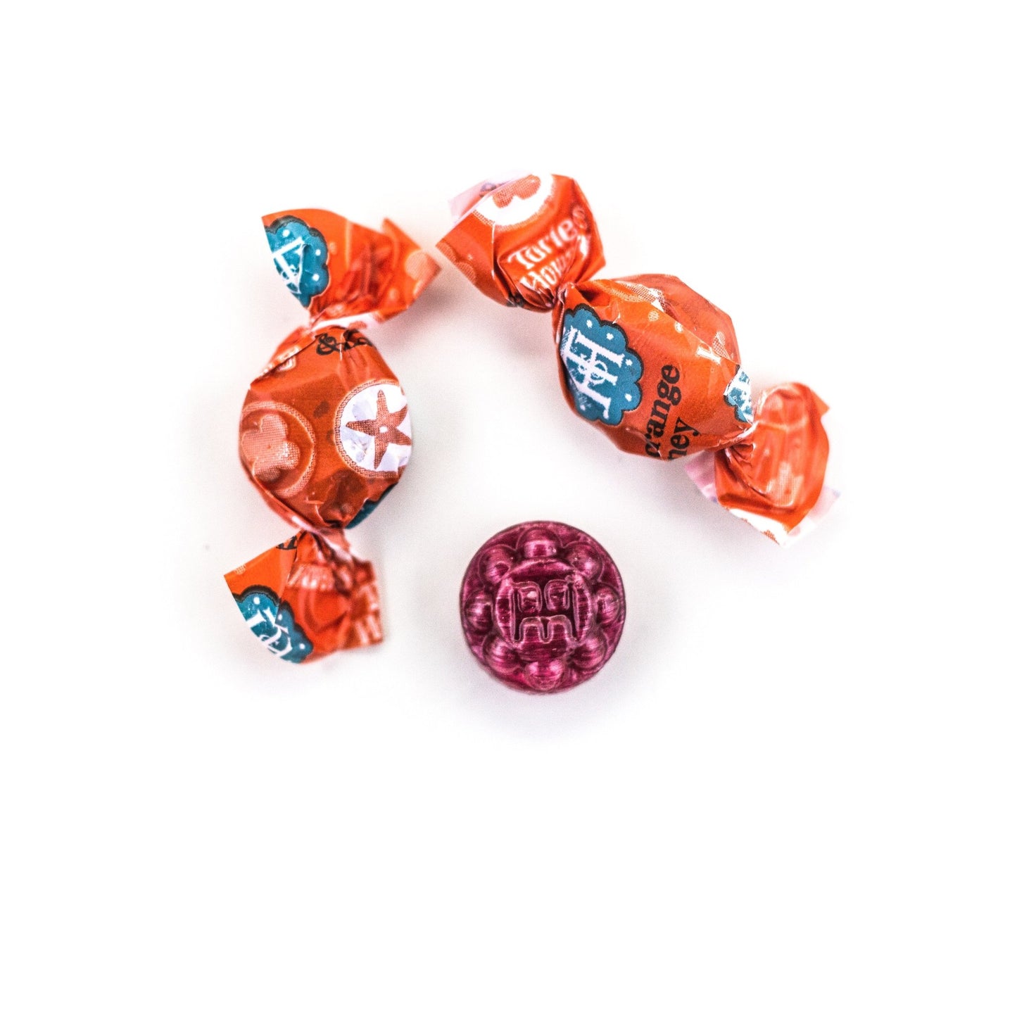 Two wrapped and one unwrapped Blood Orange & Honey Organic Hard Candies