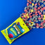 Sour Punch Gummies on a blue background with raw candy shapes falling out of the bag
