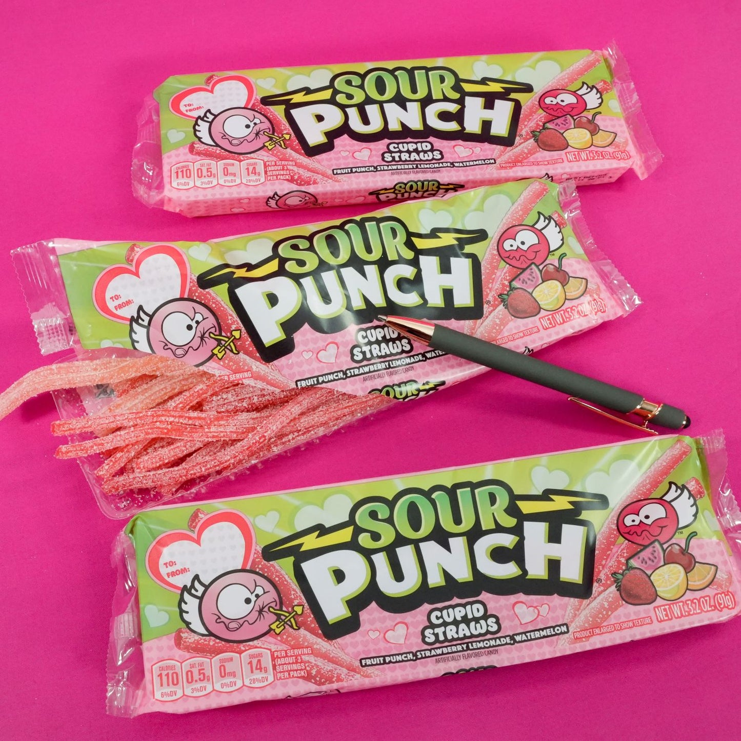 Three SOUR PUNCH Cupid Straws 3.2oz valentine candy trays on a hot pink background