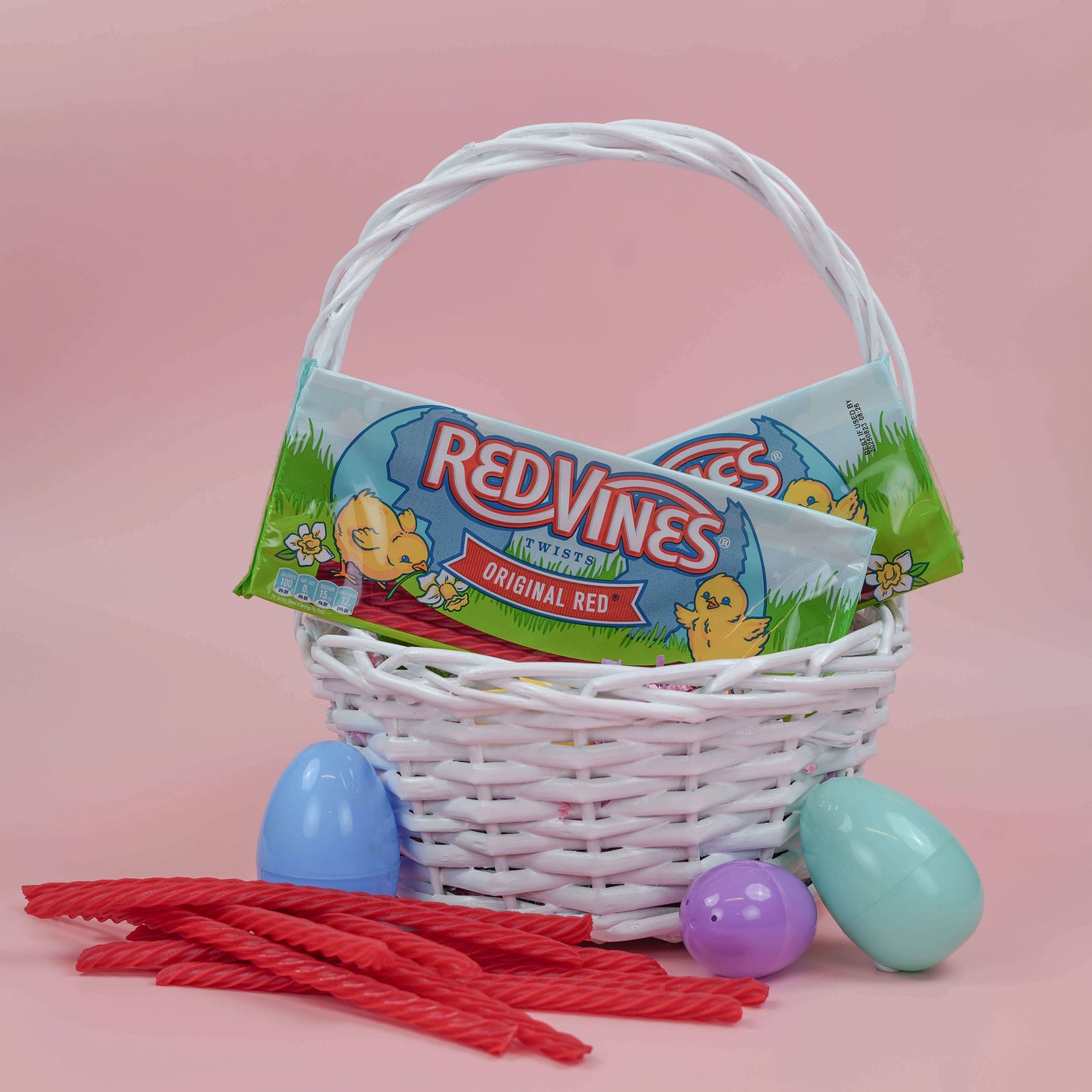 RED VINES Easter Licorice trays in an Easter basket with plastic eggs and raw candy twists in front