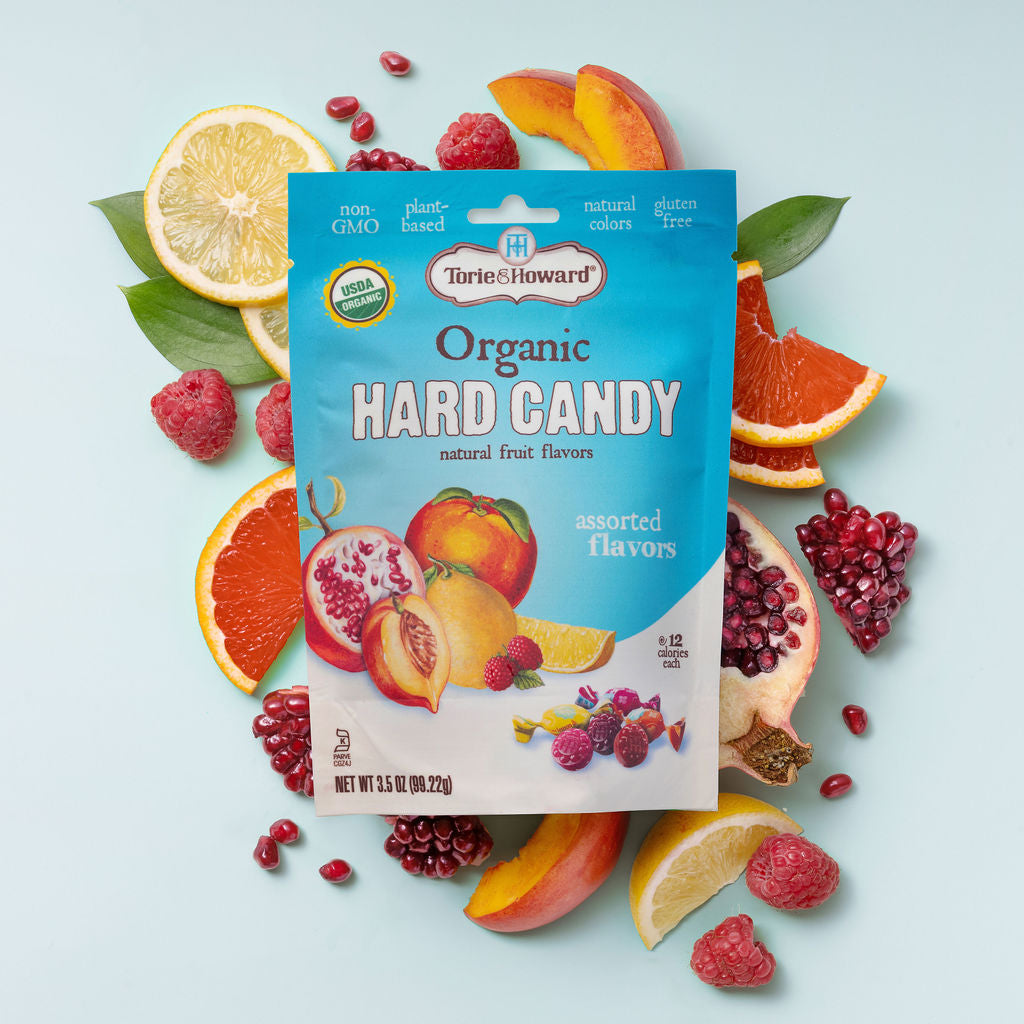 Torie & Howard Organic Hard Candy in Assorted Flavors, 3.5oz bag on top of fruit arrangement 