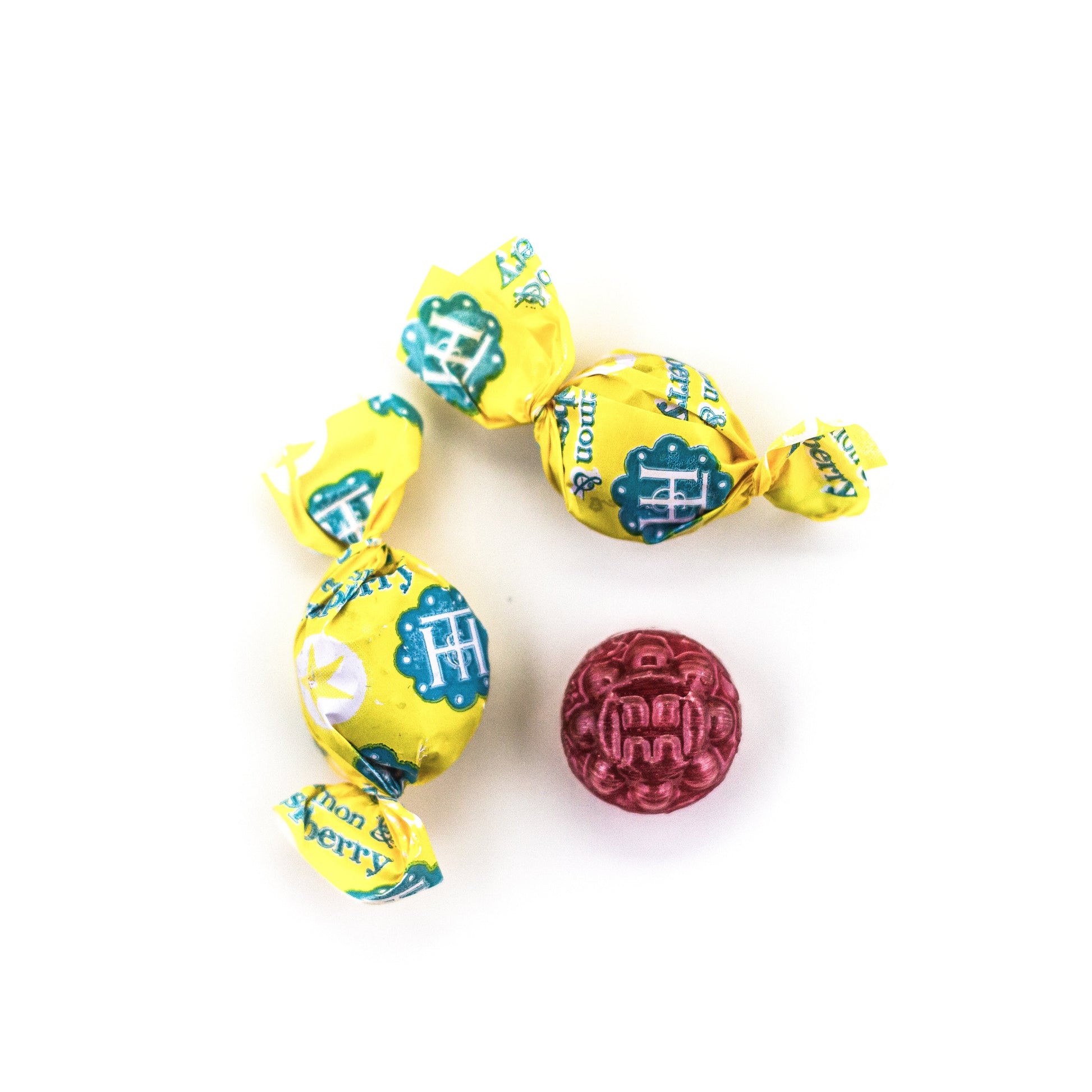 Two unwrapped and one wrapped Meyer Lemon & Raspberry Organic Hard Candies