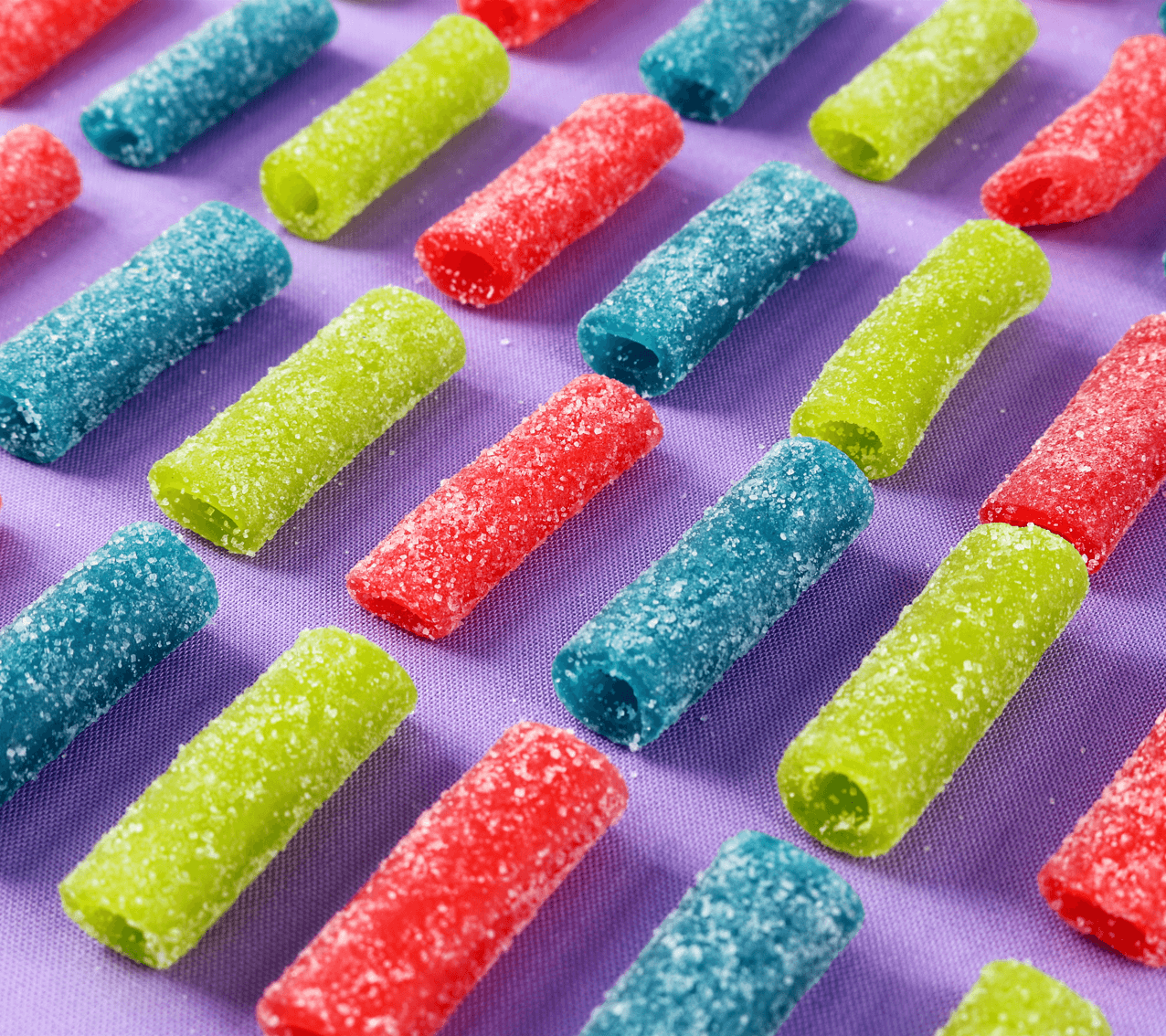 Sour sugar coated strawberry, blue raspberry, and green apple bites lined up and ready to eat
